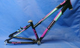 A black aluminium bicycle frame with purple and teal accents on a blue background.