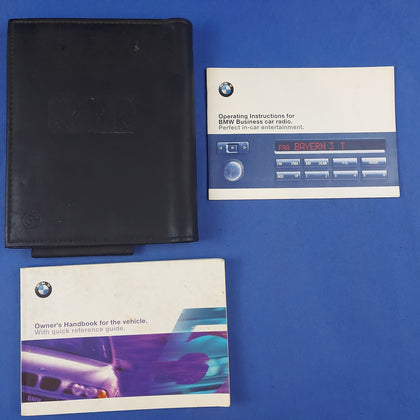 A set of BMW vehicle owner's manuals, including a black handbook and a separate booklet labeled 'OPERATING INSTRUCTIONS FOR PERFECT CAR ATTENTIVES' with the BMW logo.