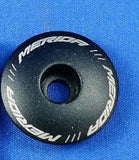 Black bicycle headset cap with 'Merida' branding on a blue background